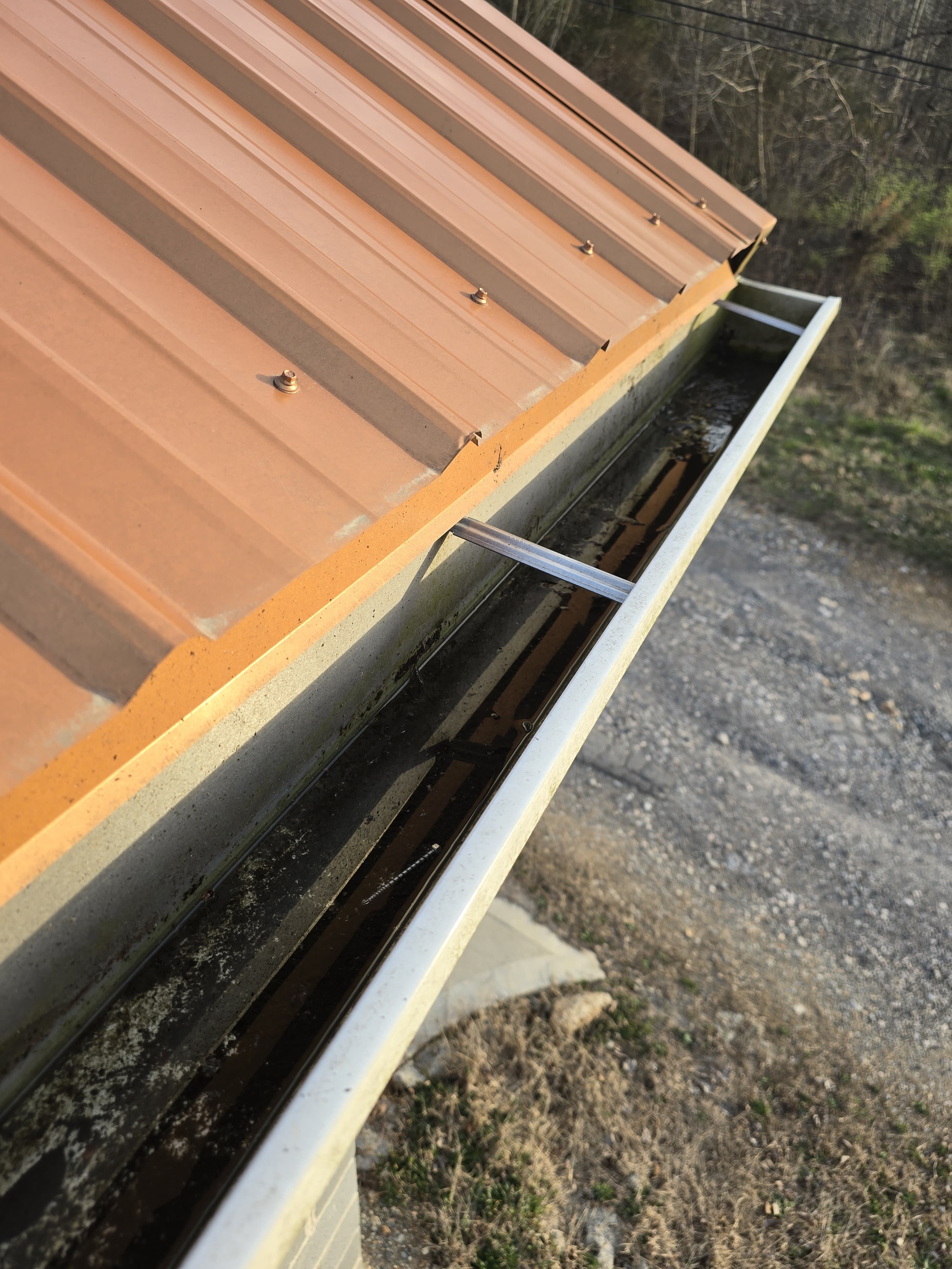 Close-up of a clogged gutter with standing water and debris — a clear sign of gutter failure